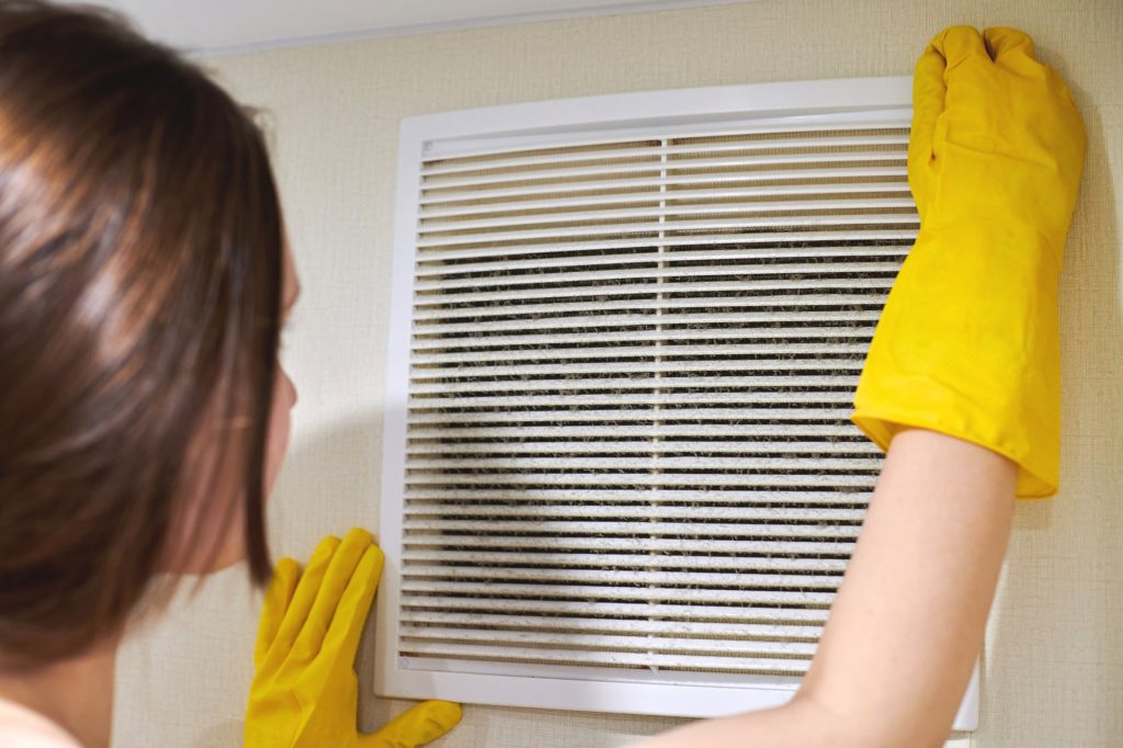 Holding ventilation grill of HVAC for cleaning or replacing.